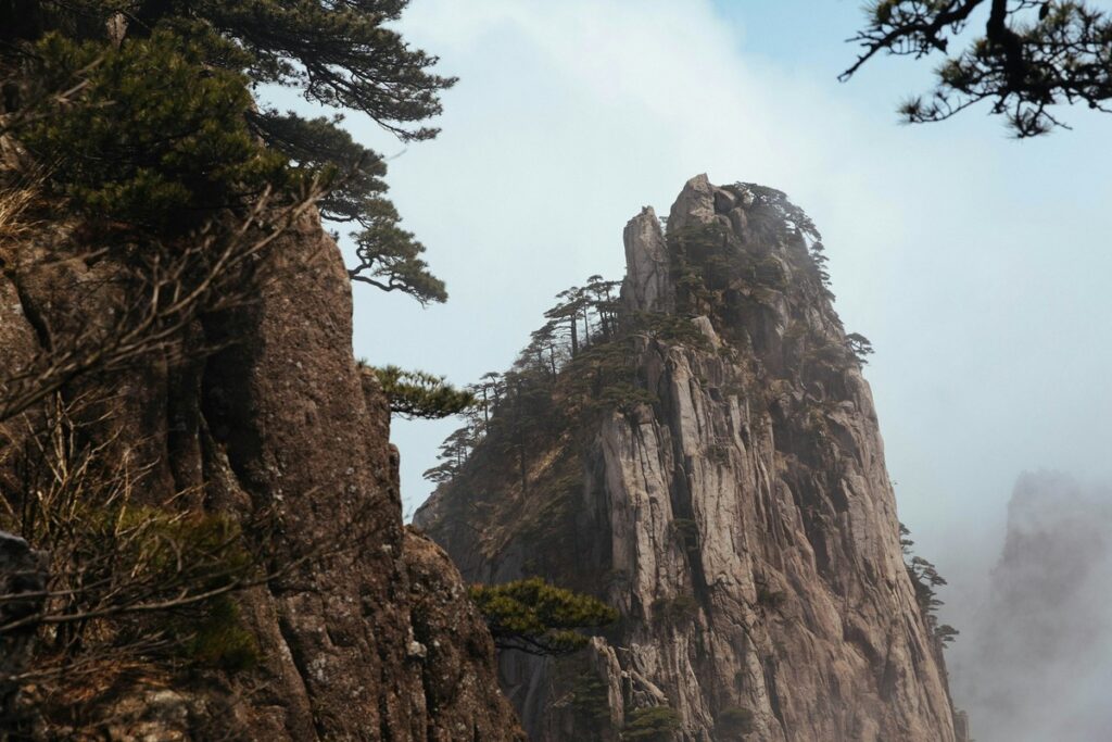 a rocky mountain with trees on top mount huangshan