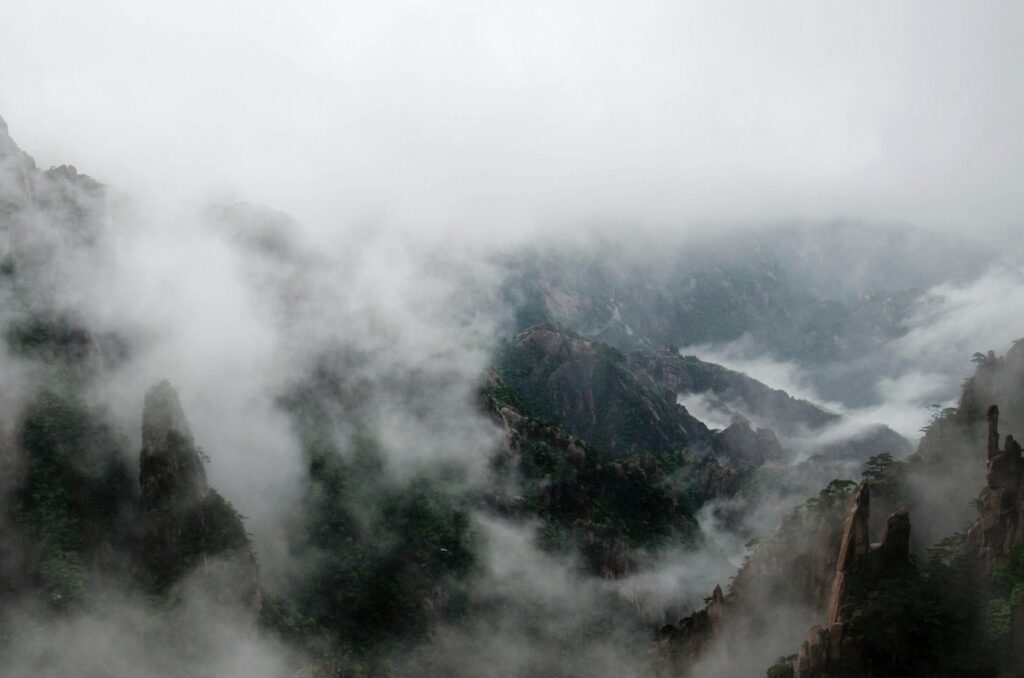 a foggy mountain range with trees and clouds mount huangshan map