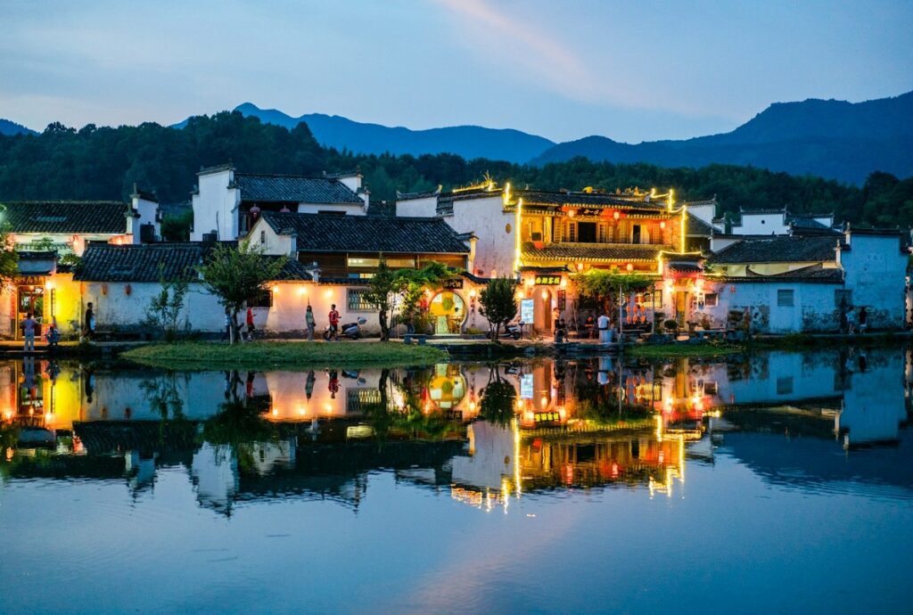 a building with lights on the side of the water mount huangshan map