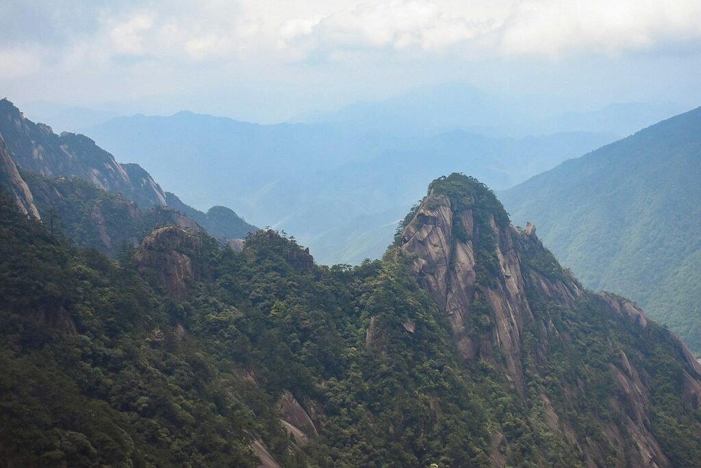 a mountain range with trees and mountains in the background mount huangshan weather