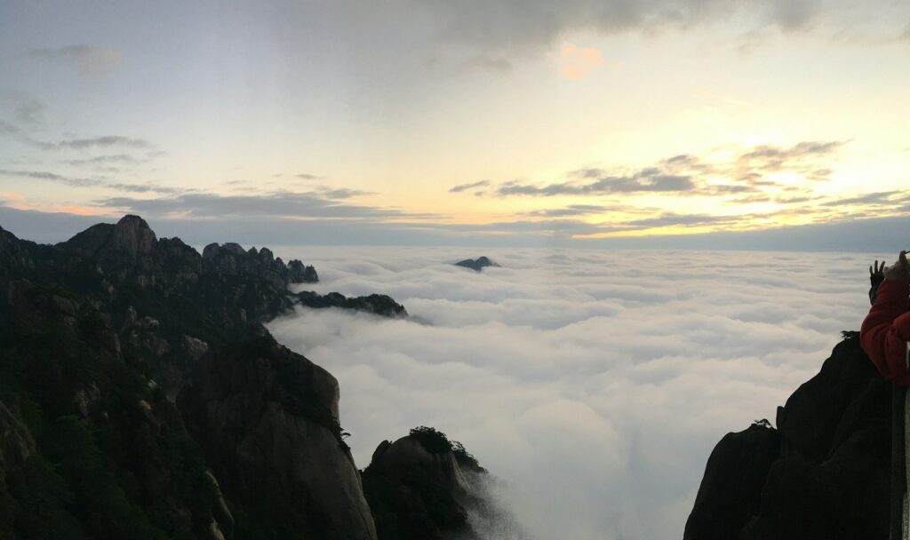 a mountain range with clouds above it yellow mountain hike china