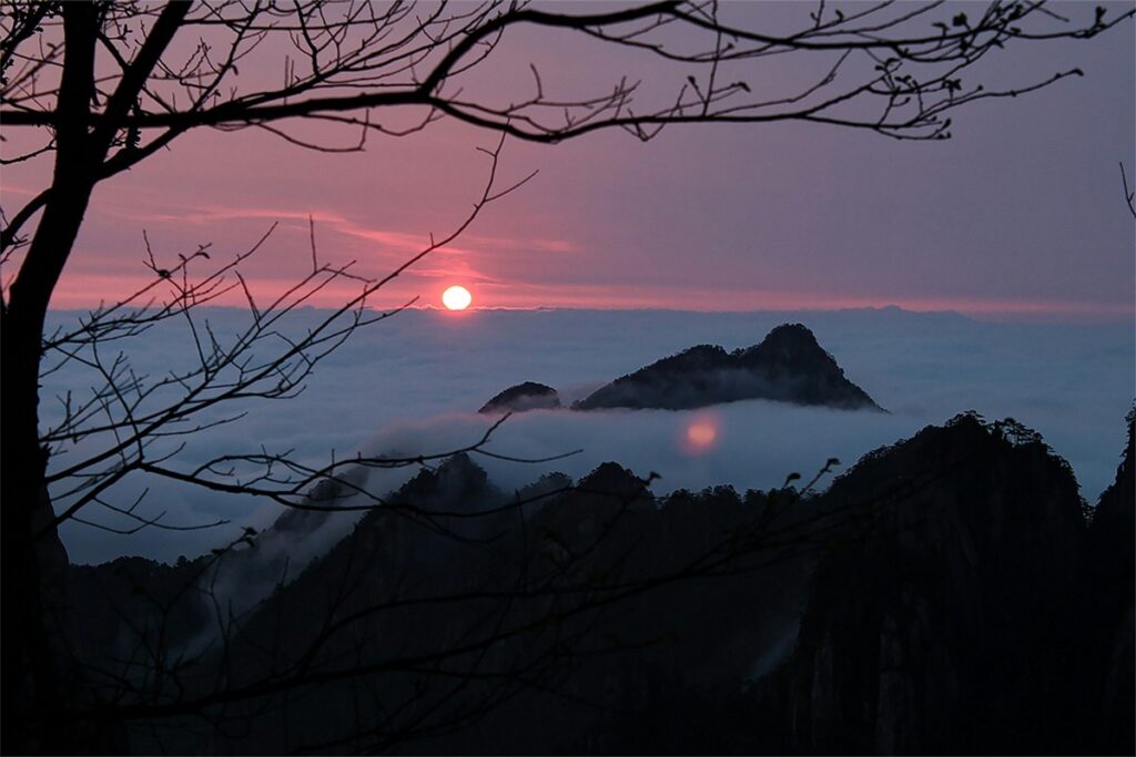 a sunset over a mountain range yellow mountain in china