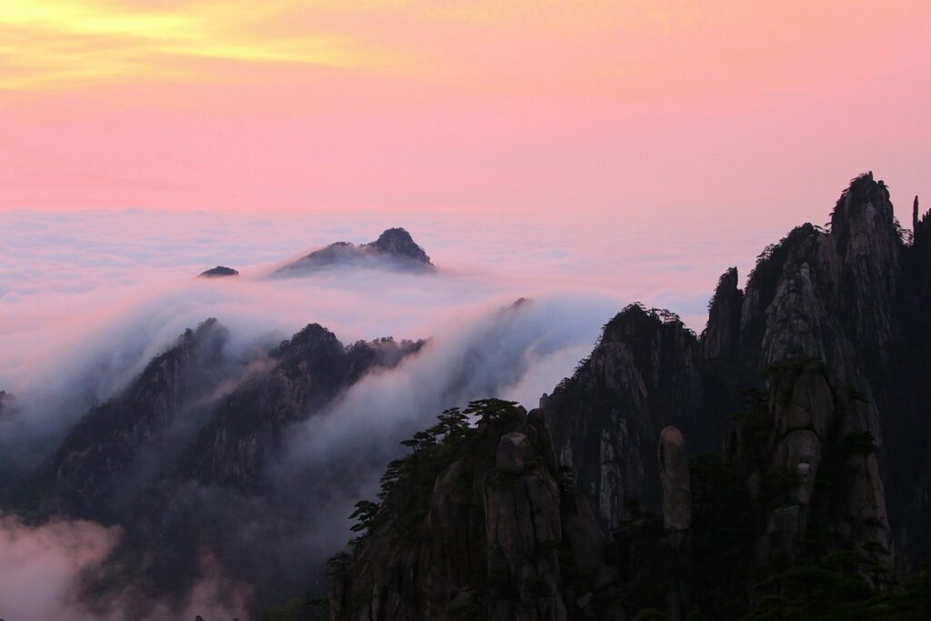 a mountain range with clouds and a pink sky yellow mountain in china