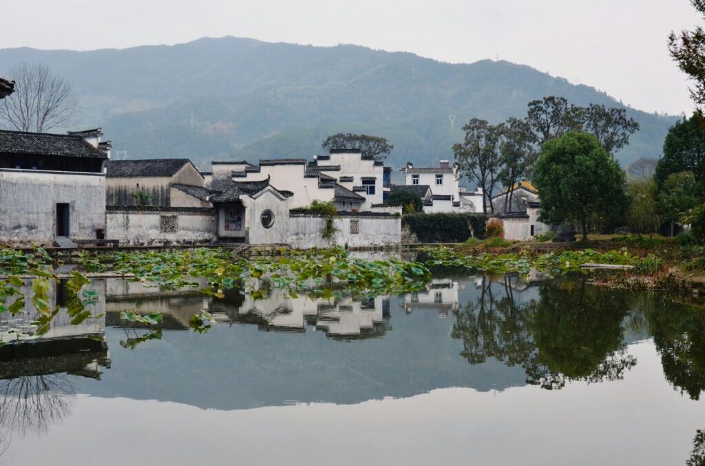 a body of water with a building and trees in the background yellow mountain of china