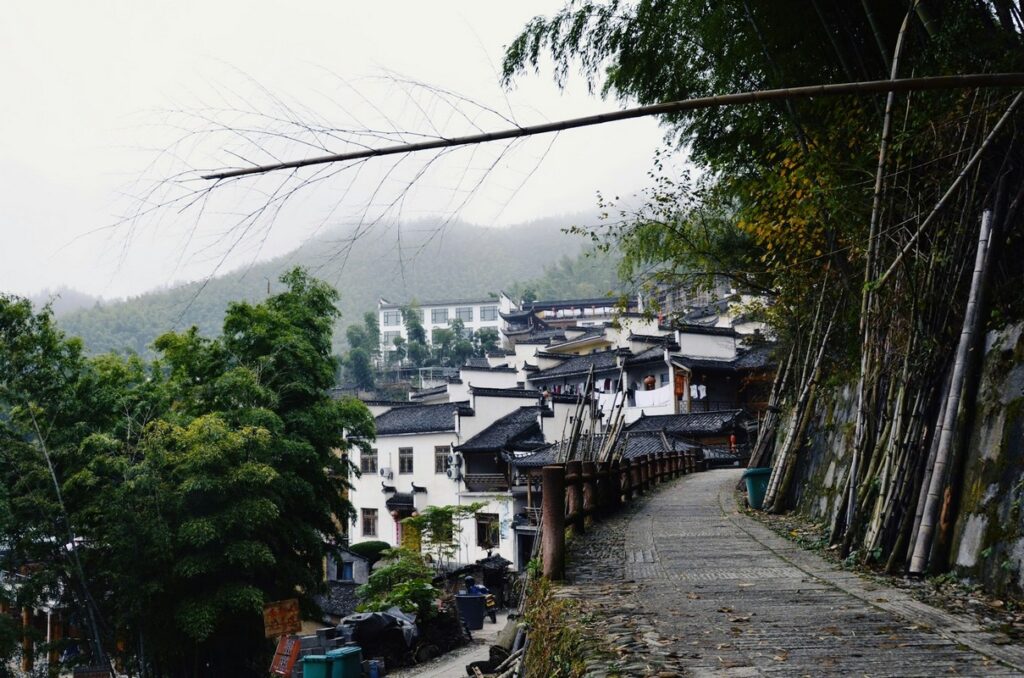 a stone path with trees and buildings in the background yellow mountain of china