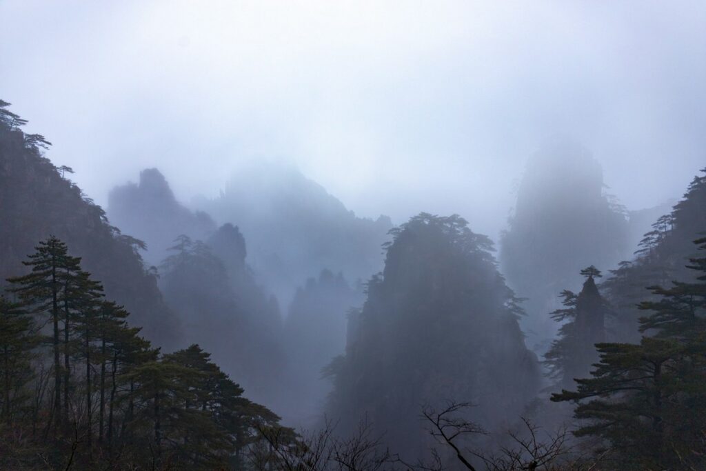 a foggy mountain range with trees with Huangshan in the background yellow mountain of china